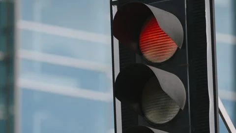 Traffic light in close up changing signal from red to green, skyscrapers behind Stock Footage 333651577
