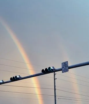 Traffic light with double rainbow as background Stock Photos
