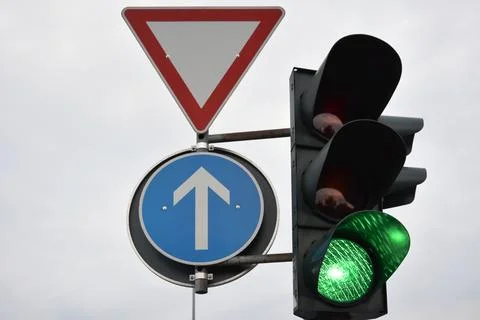 A traffic light with a green enabling light on and traffic control signs Stock Photos
