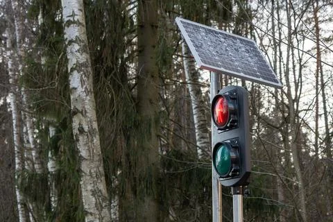 Traffic light mounted on a pole powered by solar panels. Outdoor road safety  Foto stock