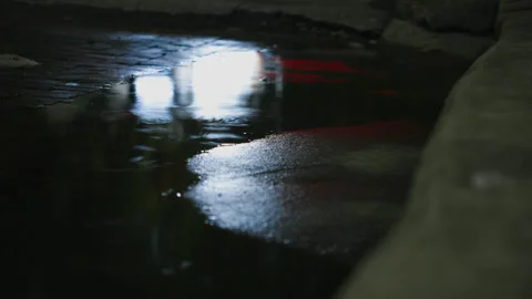 Traffic light streaks reflected in a rainy street puddle Stock Footage 345981320