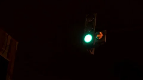Traffic light turning from green to red at a city intersection at night Stock Footage 168328611