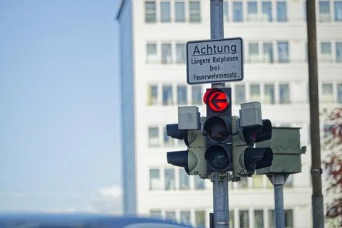 Traffic lights on a pole with warning text and red left arrow. Stock Photos