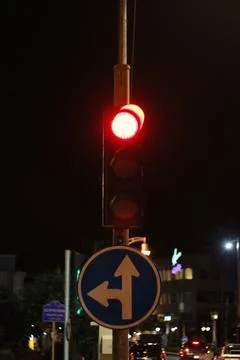 Traffic lights with red light for stop, road sign turn left and go ahead in t Stock Photos