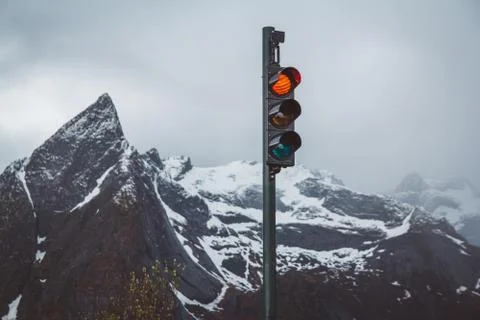 Traffic lights with red turned on the background of snow-capped mountains Stock Photos