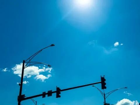 Traffic lights stand under a clear blue sky on a sunny daytime in an urban ar Stock Photos