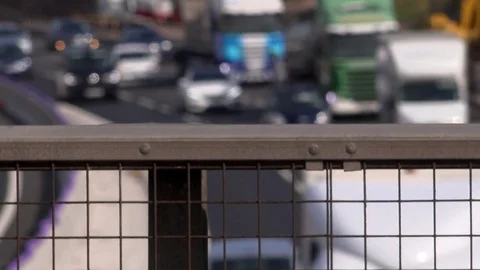 Traffic moves on road with wire railing in foreground Manchester England 4K Vidéo 77783229