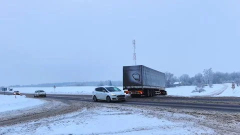 Traffic moves through a snowy intersection in winter conditions during early mor Stock-Footage 328489346