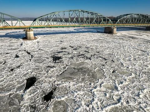Traffic moving along bridge over river covered in ice floes. Stock Photos