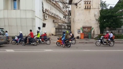 Traffic next to building with air-con units, people ride motorbikes, Laos Stockbeeldmateriaal 75247867