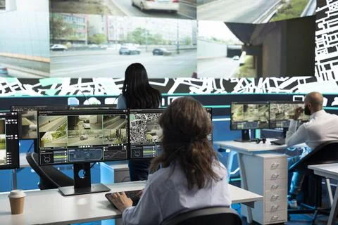 Traffic operators working at desks, analyzing road camera footage on videowall Stock Photos