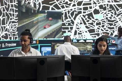 Traffic operators working at workstation desks, controlling road cameras Stock Photos