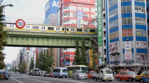 Traffic passes under a rail bridge on a busy downtown Tokyo main street. Stock Footage 97849300