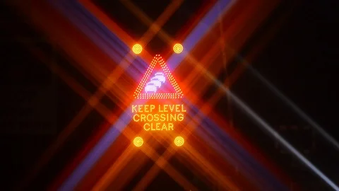 Traffic passing flashing keep level crossing clear warning sign at night uk Stock Footage 85598211