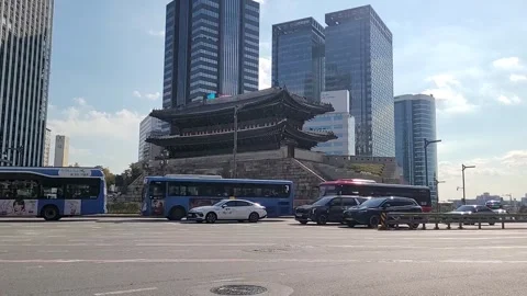 Traffic Passing in Front of Sungnyemun Gate with Modern Skyscrapers Video stock 321011384