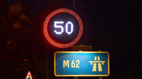 Traffic passing reduced speed 50mph limit warning sign on m62 uk Stock Footage 85010232