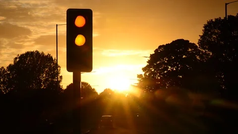 Traffic passing traffic light changing from red to green at sunset uk Stock Footage 95579604
