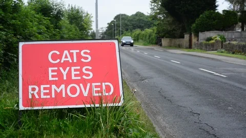 Traffic passing warning sign of cats eyes removed on road ahead uk Stock Footage 90649712