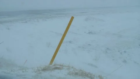 Traffic post in a snowstorm and a snowdrift on and by the asphalt road. Stock Footage 152949956