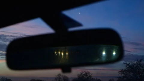 Traffic reflected in drivers rear view mirror at sunrise uk Stock Footage 123343732