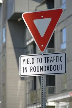 Traffic sign instructing drivers to yield in a roundabout Stock Photos