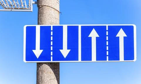 Traffic sign pointing multiple road lanes direction on city street. Blue ro.. Stock Photos