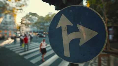 Traffic sign shows direction to continue straight or turn left in busy street in Stock Footage 346381728