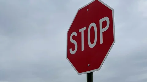 Traffic stop sign moving in the wind against cloudy sky Video stock 126950452