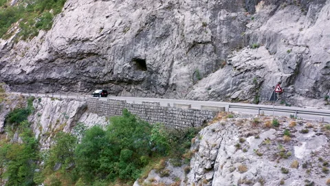 Traffic on a two lane mountain road cut in rocky hillside Stock Footage 159842904