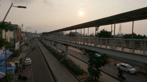 Traffic under the empty pedestrian bridge leading to the Transjakarta bus stop Stockbeeldmateriaal 153807979