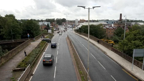 Traffic viewed from over pass flows in and out of England town Stock Footage 96224376
