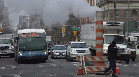Traffic waiting at a light before driving past a steaming smoke stack Stock Footage 51306258