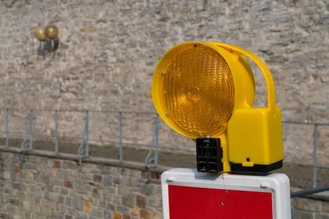 Traffic warning light by stone wall. Close up. Stock Photos