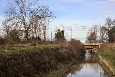 Trail bordered by a stream of water with a railroad crossing over an embank.. Stock Photos