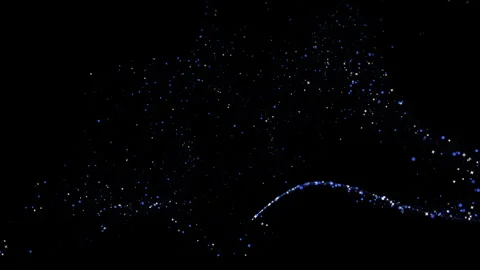 A trail flying along a bizarre trajectory, scattering white and blue sparkli Stock Footage 255379746