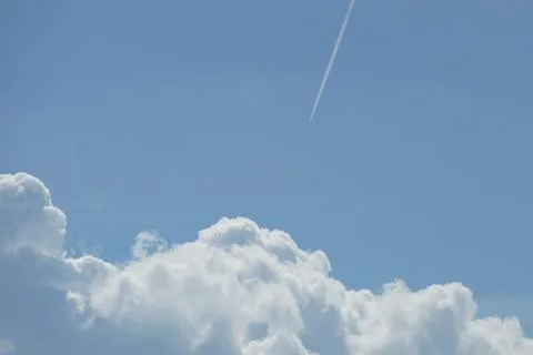 Trail from a jet plane white clouds blue sky Stock Photos