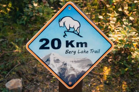 A trail marker indicates the direction and distance of a hiking path. Stock Photos