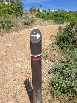 Trail marker post points the way on a sunny dirt path in a Mediterranean na.. Foto stock