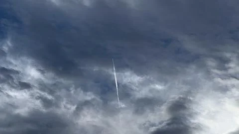The trail of a plane in the cloudy sky Stock Photos