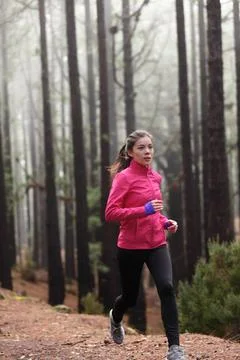 Trail run fit active Asian runner athlete woman jogging in woods early morning Stock Photos