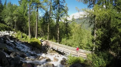 Trail runner crossing rapid creek above the wood bridge. Slow motion Stock Footage 53932196