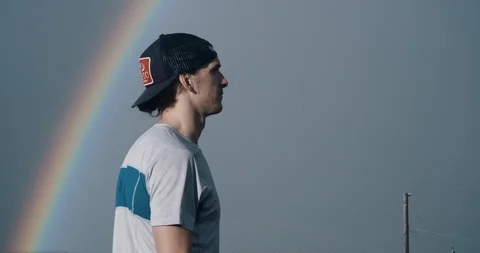 Trail runner removing hat with rainbow in background Stock Footage 98438253