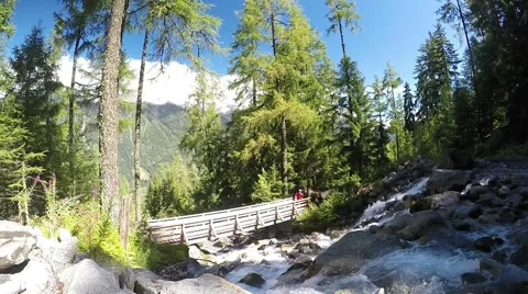 Trail runner runs on the bridge in Chamonix valley near the rapid stream Stock Footage 53875094
