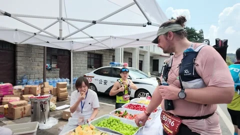 Trail Runner Taking Fruit at Aid Station with Volunteers, Lushan Race Video stock 346717655