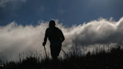 Trail runner using hiking poles on a mountain with dramatic clouds Stock Photos