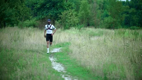 Trail runner wearing hydration vest jogging along grassy path through meadow Stock Footage 313951360