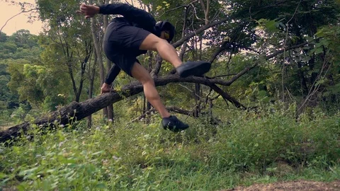 Trail running man exercising in the woods and jumping over logs while. Stock Footage 104493276