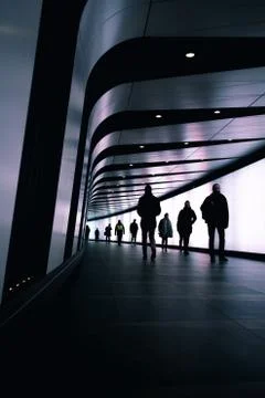Trail of shadowy figures walking in order in one direction and one man shadow Stock Photos