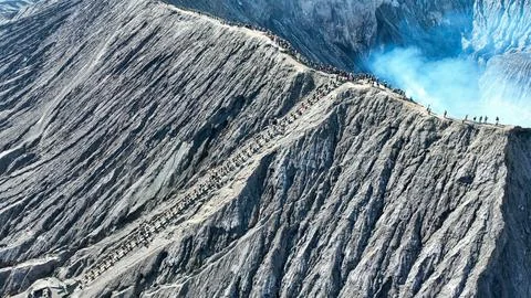 The trail snakes up Bromo flank to its smoking blue heart, surrounded by rippled Foto stock