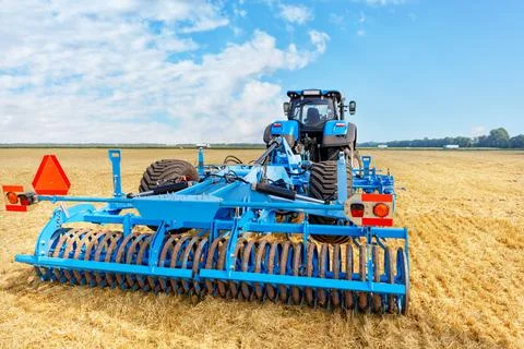 Trailed blue harrow as a trailed implement on a tractor against the backgroun Stock Photos